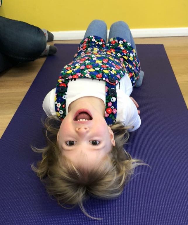 child lying on the floor practicing a yoga pose