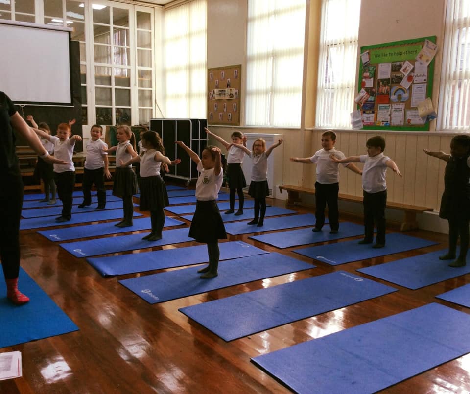 kids standing on their mats with arms in the air