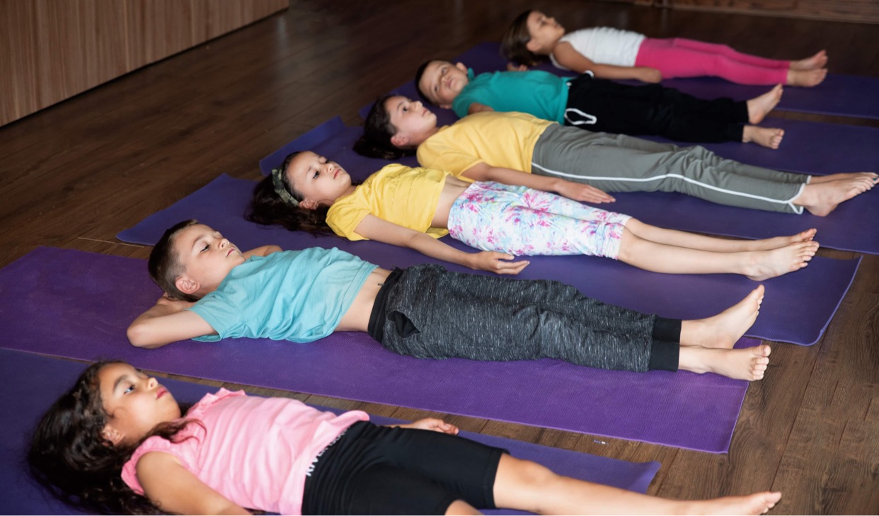 six children relaxing on yoga mats in studio during a minds and wellbeing class