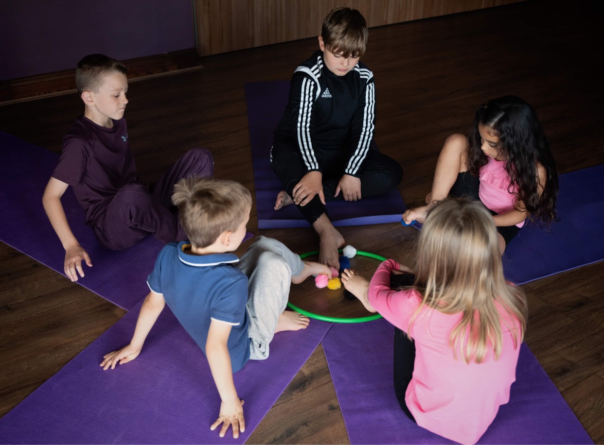 children playing a yoga game picking up pom poms with their feet
