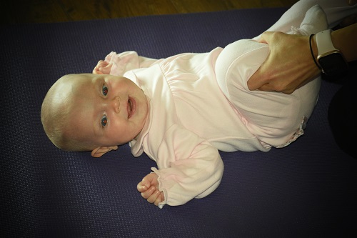 baby lying on a yoga mat in a baby yoga class