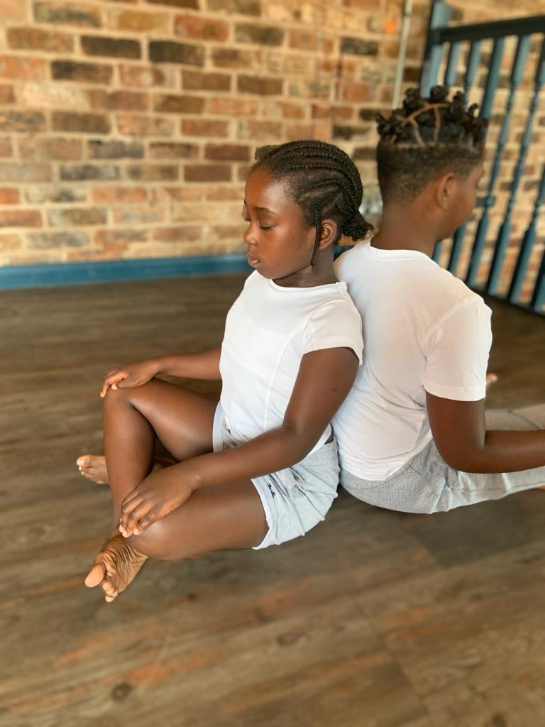 2 children sat back to back in a mindfulness pose
